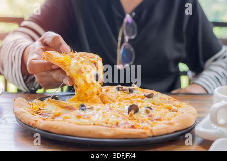 Woman hand taking slices of delicious pizza from plate in a restaurant. Hands and homemade pizza. Food concept. Stock Photo