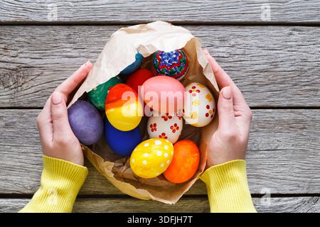 Colorful Easter Eggs in a Basket Held by Hands on a Rustic Wooden Table Stock Photo