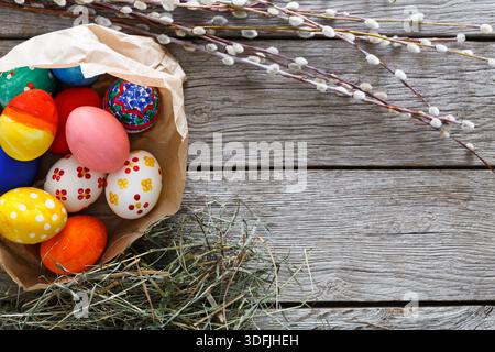 Colorful Easter Eggs in a Paper Bag Surrounded by Spring Decorations on Wooden Table Stock Photo