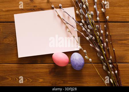 Colorful Easter Eggs and Blank Card With Willow Branches on Wooden Table Stock Photo