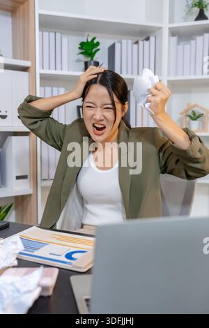 Stressed businesswoman dealing with heavy work pressure, reacting emotionally while reviewing reports and facing tight deadlines, highlighting workpla Stock Photo
