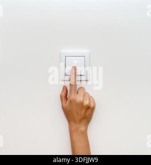 Female hand turning off light switch for energy saving. Stock Photo