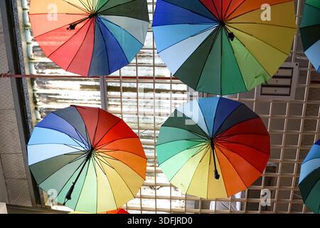 Vibrant umbrellas arranged in rows against a grid background, creating a symmetrical and colorful visual pattern. Stock Photo