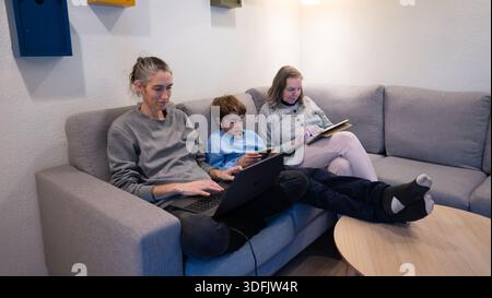 Family members across generations using gadget together while relaxing on sofa at home Stock Photo
