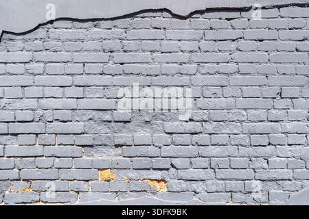 An old brick wall is painted with gray paint. Abstract construction background. Stock Photo