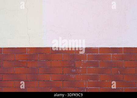 Half of the red brick wall is painted over with white plaster. Abstract construction background. Stock Photo