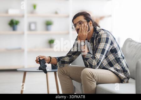 Upset middle-eastern guy got bored while playing video games Stock Photo