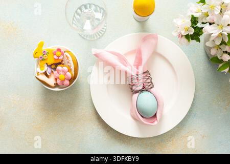A vibrant Easter table setting features a beautifully arranged plate with a wrapped egg, decorated cookies, and fresh flowers, creating a joyful atmosphere for the holiday gathering Stock Photo