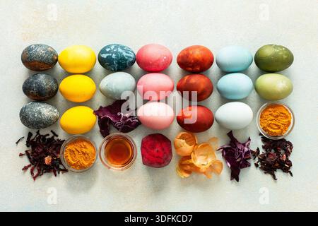 Brightly colored Easter eggs , showcasing various hues created from natural dye sources. Fresh ingredients are displayed alongside such as beets, turmeric and hibiscus, red cabbage and onion peel, vinegar Stock Photo