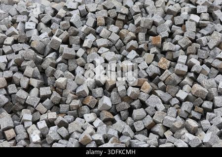 High-Angle Pile of Natural Grey Granite Cobblestone Pavers for Landscaping and Urban Construction Stock Photo
