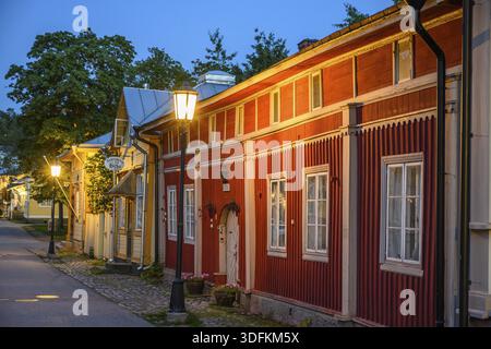 Street scene in the old town of Naantali, red historic wooden building with decorative windows on a paved street in the evening light with cozy street Stock Photo