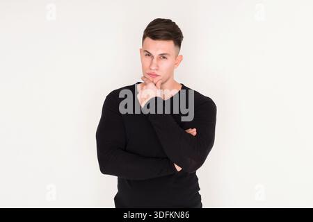 Thoughtful Young Man Posing With Arms Crossed in a Minimalist Setting Stock Photo