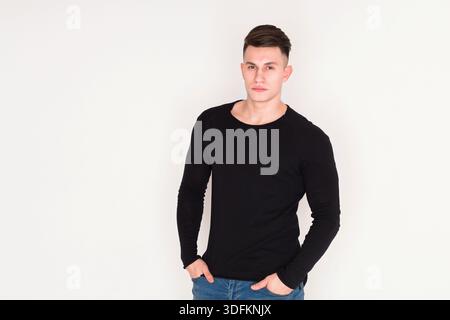 Young Man Poses Confidently Against a Plain Background With a Stylish Look in Casual Clothing Stock Photo