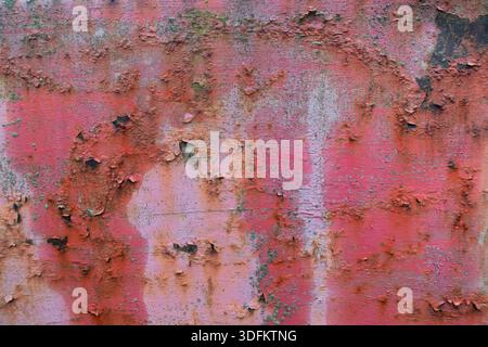 Weathered pink wall with peeling paint, rust stains and rough texture, expressing urban decay and aged architectural surface Stock Photo