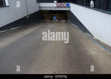 Empty underground parking garage entrance with concrete ramp, clean lines and urban architectural simplicity Stock Photo