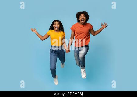 Excited african american lovers holding hands while running Stock Photo