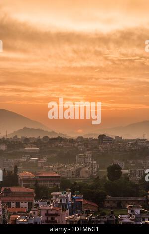 A breathtaking sunset featuring a large, radiant yellow sun dipping below the horizon. The sky is painted in warm shades of orange, gold, and soft pin Stock Photo