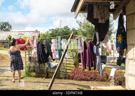 oment of daily life, Bohol, Philippines, woman is hanging laundry on a clothesline outdoors. Stock Photo
