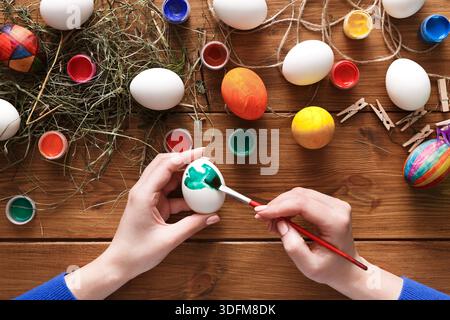 Creative Easter Egg Decorating Activity With Paint and Colors on a Wooden Table Stock Photo