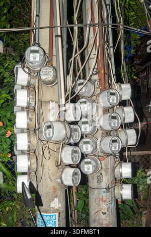 cluster of electricity meters mounted on utility poles, devices measure the amount of electrical energy consumed by a residence, Cebu, Philippines Stock Photo