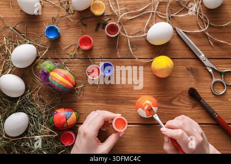 Creative Easter Egg Decoration Activity With Paints and Tools on Wooden Table Stock Photo