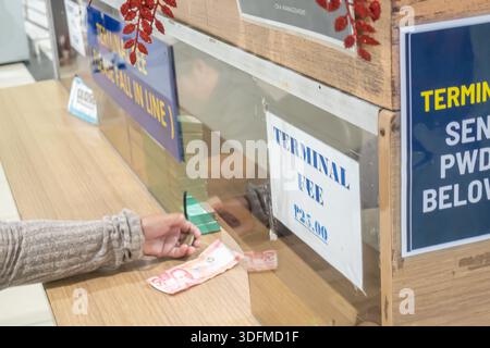 A person paying a terminal fee of 25 PHP in ferry terminal, Cebu, Philippines. Stock Photo