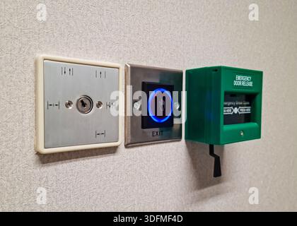 Multiple building access control devices mounted on a textured interior wall. Components include a key switch for security override, a sensor-based to Stock Photo