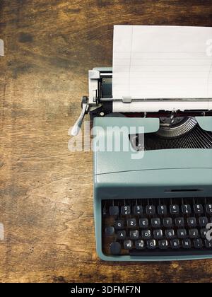 Portable typewriter isolated on a wooden background. Vintage Italian item. Overhead view. Stock Photo