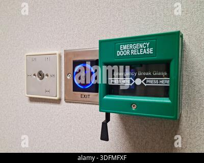 Multiple building access control devices mounted on a textured interior wall. Components include a key switch for security override, a sensor-based to Stock Photo