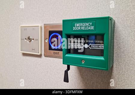 Multiple building access control devices mounted on a textured interior wall. Components include a key switch for security override, a sensor-based to Stock Photo