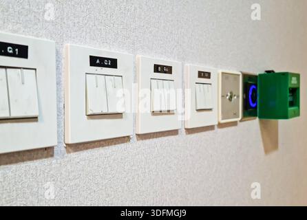 Multiple building access control devices mounted on a textured interior wall. Components include a key switch for security override, a sensor-based to Stock Photo