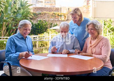 Senior adults are doing cognitive rehabilitation exercises with a nurse outdoors at a rehab center. This image can be used for brain injury recovery a Stock Photo