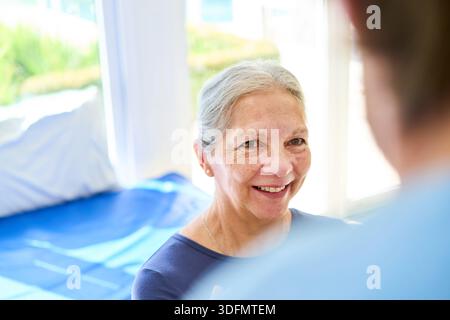 A senior woman is smiling during a physiotherapy session with her therapist in a rehab center. This image can be used for recovery rehabilitation and Stock Photo