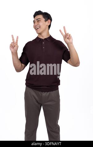Young Man Gesturing Peace Symbol and Smiling on White Background Stock Photo