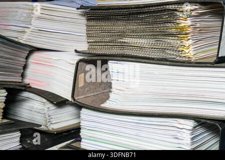 Close-up of piled accounting document folders filled with paperwork, illustrating office bureaucracy, record keeping, audits, and administration Stock Photo