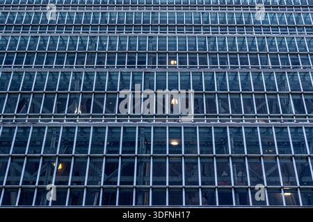 A grid of glass panes framed by metal, revealing internal steel structures and occasional interior lights  in Edinburgh, Scotland. Stock Photo