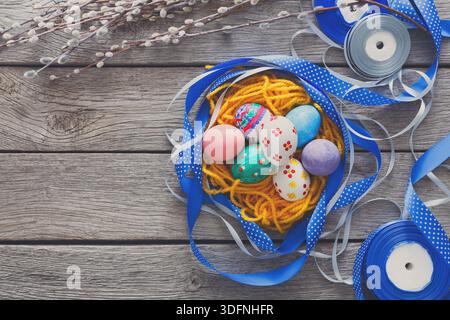 Colorful Easter Eggs Surrounded by Ribbons and Spring Decorations on a Wooden Background Stock Photo