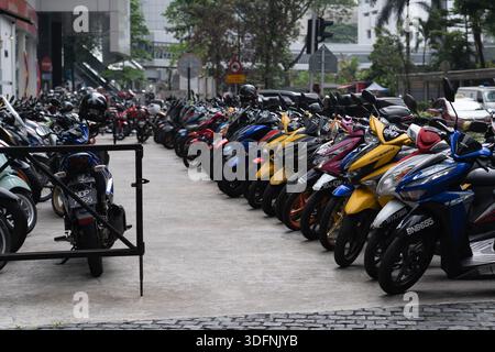 Parking lot with scooters and motorcycles in front of Bank Islam building and modern skyscrapers under a cloudy sky, Kuala Lumpur, Malaysia. Stock Photo