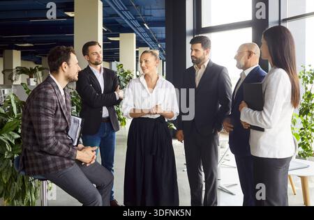 Team of successful business people standing in office room, discussing something, enjoying team work Stock Photo