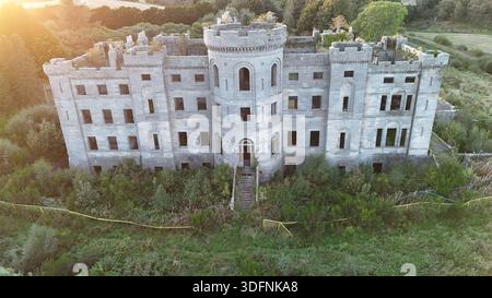 Aerial view of the abandoned ruins of Dalquharran Castle, a late-18th-century Gothic-style mansion set within woodland near River Girvan in Ayrshire Stock Photo