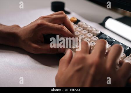 Close-up cropped shot of mechanical keyboard featuring vibrant keycaps, illuminating workspace during concentrated typing under soft ambient lighting. Stock Photo
