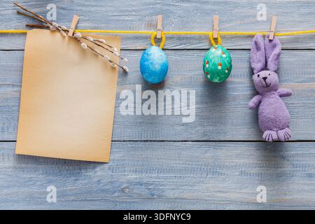 Colorful Easter Decorations With Eggs and a Bunny on a Wooden Background Featuring a Blank Note Stock Photo