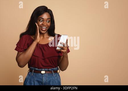 Emotional black woman using nice mobile app on smartphone Stock Photo