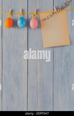 Colorful Easter Eggs Hanging on a String With an Empty Note on a Wooden Background Stock Photo