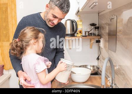 Family man and girl cook pancakes in kitchen, father and daughter spend time together Stock Photo