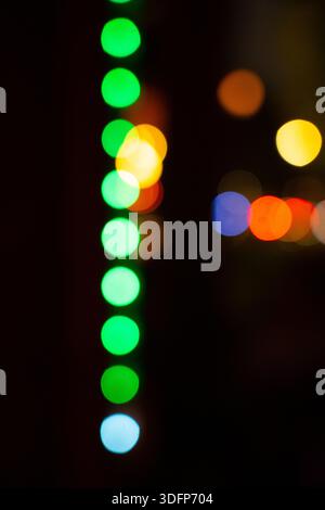 abstract of vertical column of green lights in bokeh multicolored lights in the background abstract technology christmas or blurred vision backdrop Stock Photo