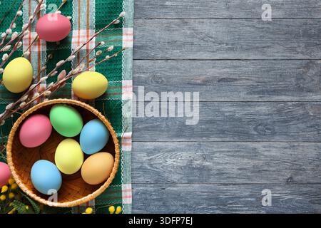 Colorful Eggs in a Woven Basket on a Green Fabric Background With Spring Decorations Stock Photo