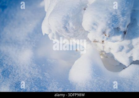 Macro view of powder snow surface and rounded snow chunks with small dirt specks, bright natural light creating clean abstract background texture Stock Photo