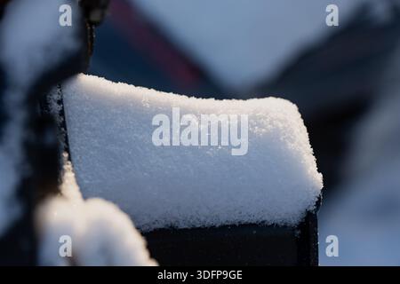 Snow covered metal object in close view, clean white snow cap with glittering crystals and soft bokeh background, minimalist cold season texture scene Stock Photo