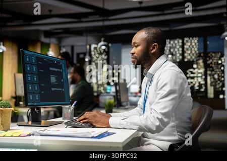 Young man programming software code on his desktop computer, using coding language for debugging tasks. Workspace with high tech helps with digital engineering and web development. Stock Photo